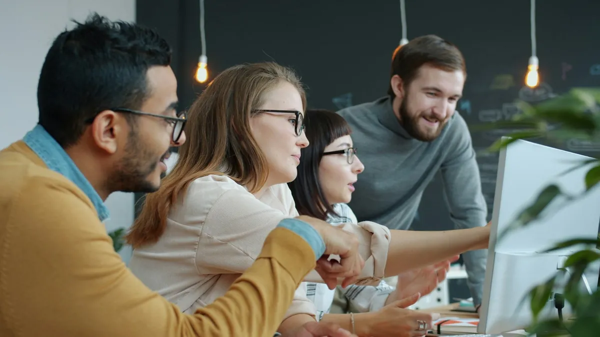 Equipe de uma pequena empresa conversando em volta do computador